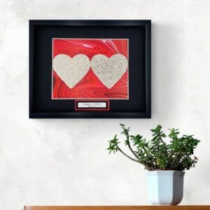 Framed artwork with two heart shapes on a red background.