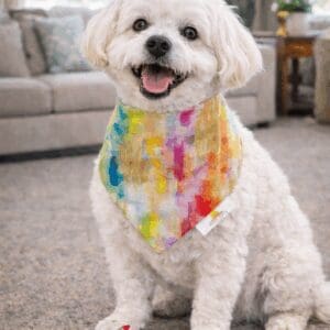 Smiling white dog wearing colorful bandana with crayons